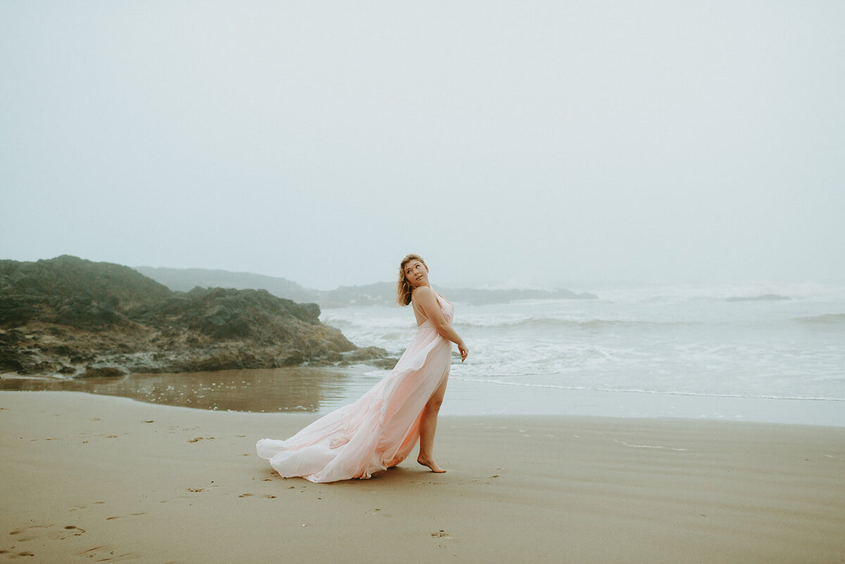 girl in pink dress walking on the beach