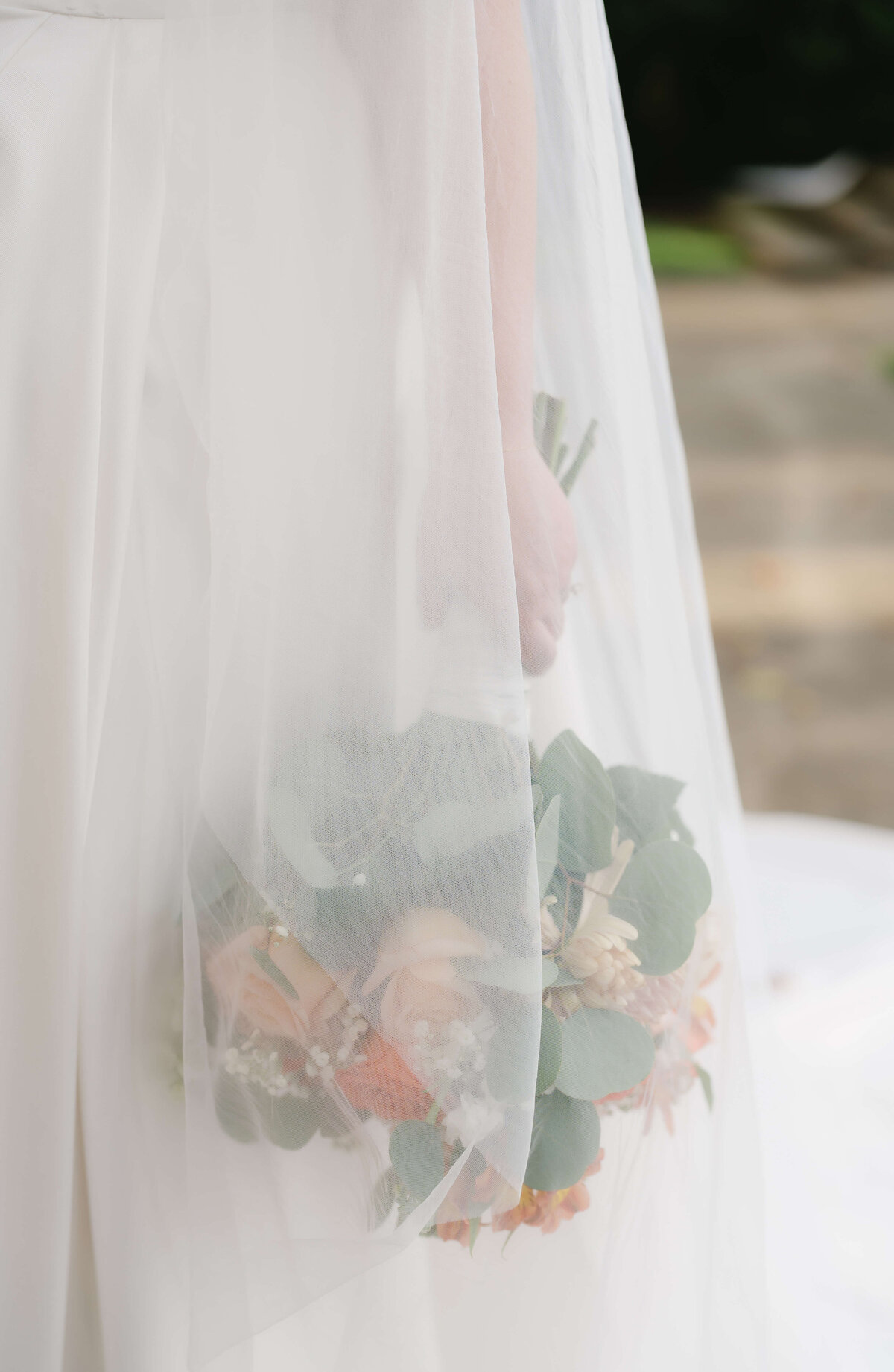 bride holding her floral bouquet to her side as her veil drapes over the flowers captured by Virginia wedding photographer