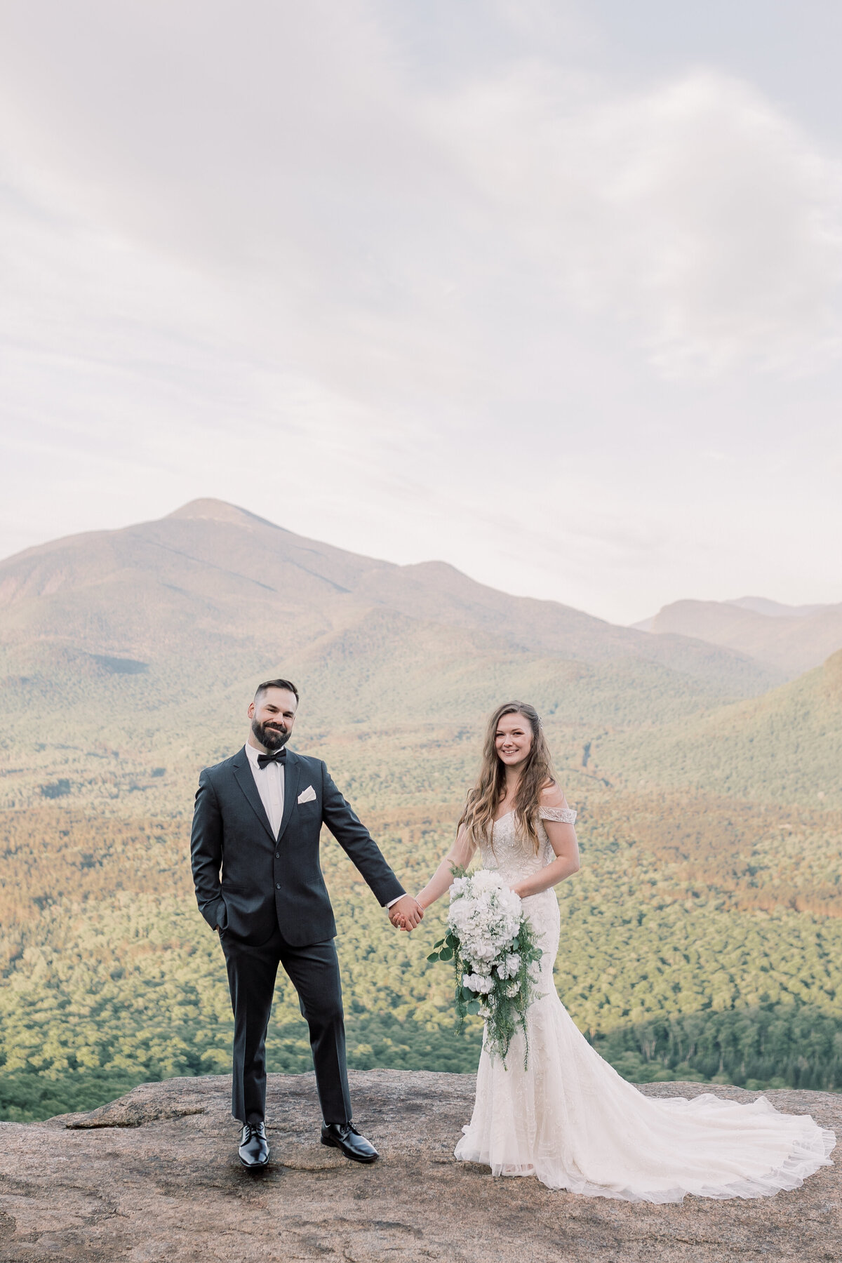 Bride and Groom standing on top of a mountain in the Adirondacks celebrating their elopement at sunrise.