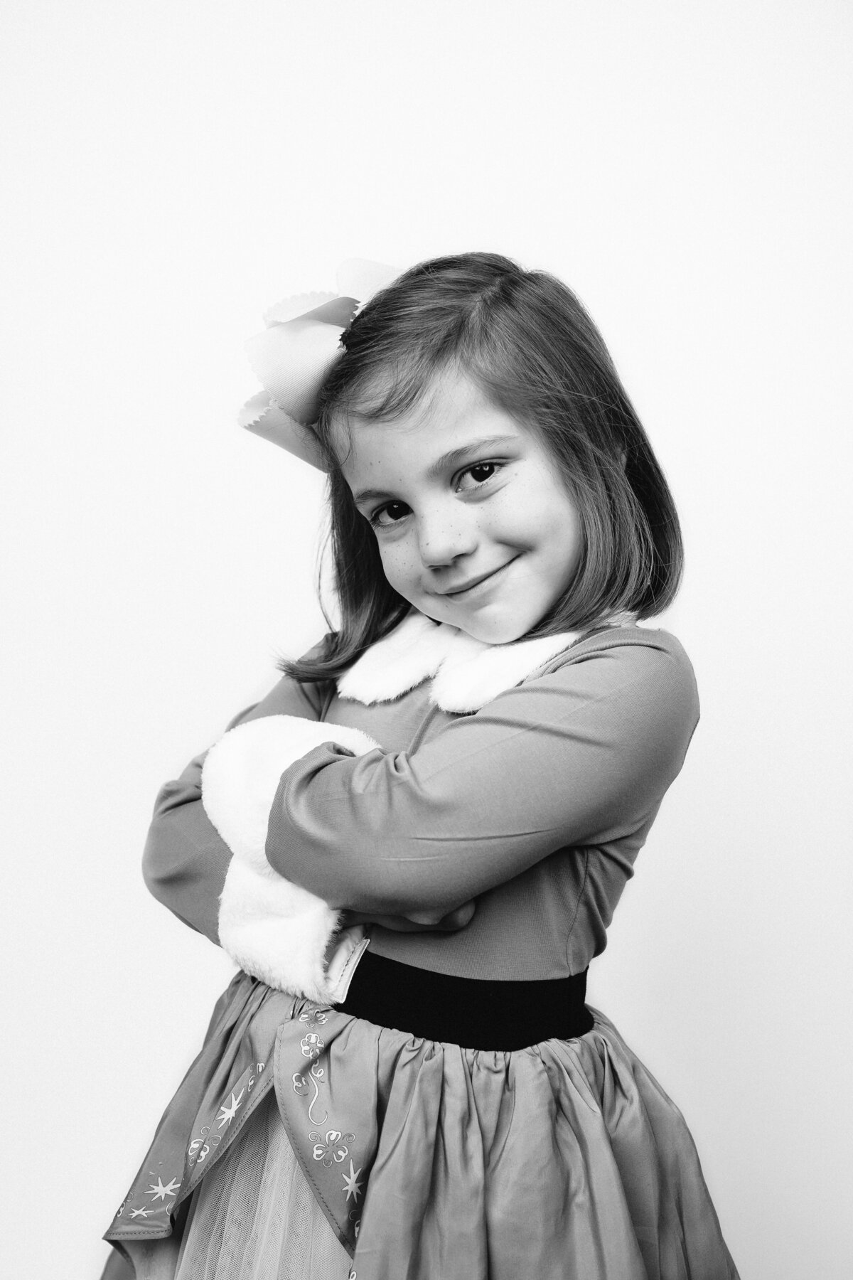 Closeup Black and White photo for girl dressed in Buddy the Elf inspired costume with her arms crossed and smiling.