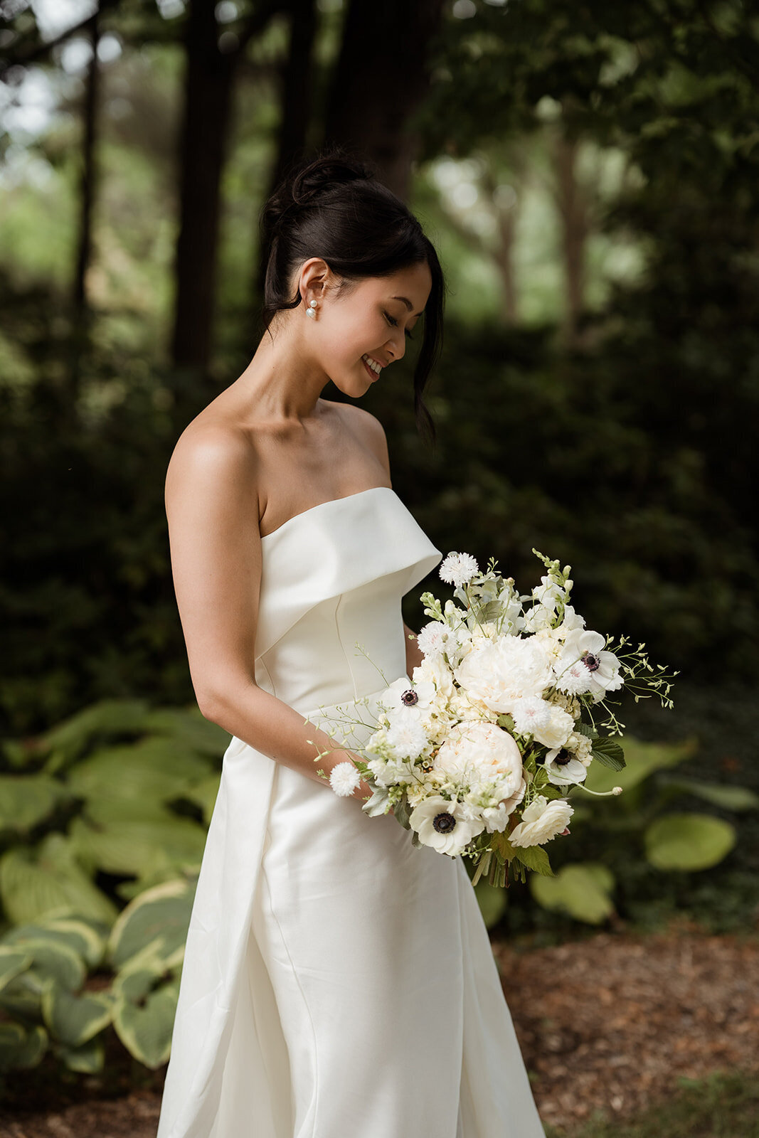 A bride holds an elegant bouquet of white flowers in the garden of La Toundra.