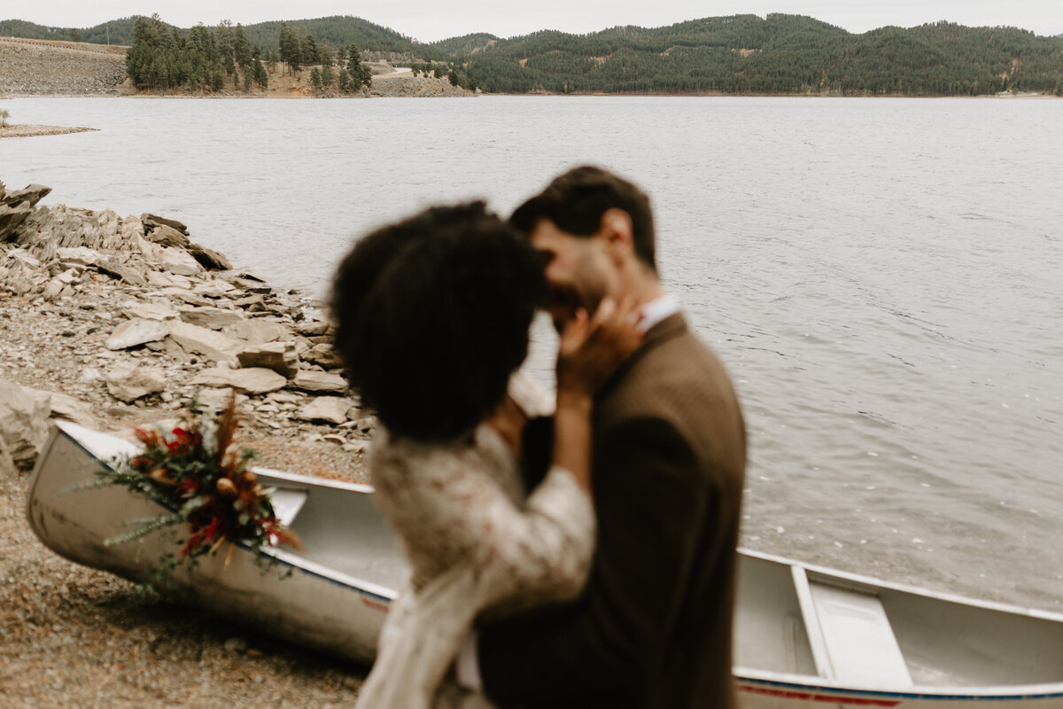 lakeside elopement with couple kissing in front of lake and canoe mariah jones photography