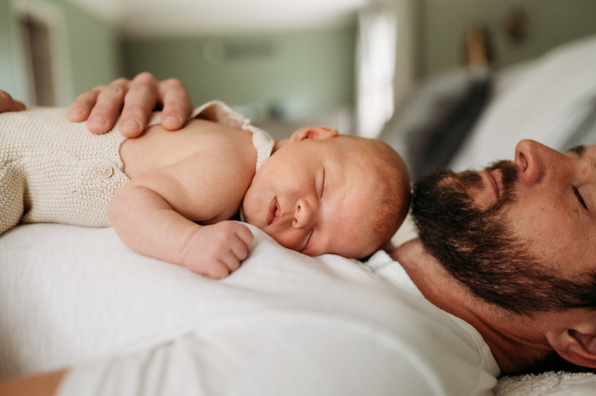 Baby rests on father's chest in the family bed.