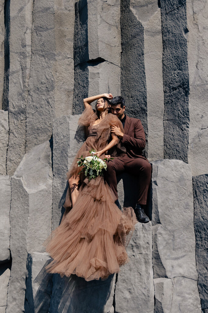 Stylish couple posing in front of rock structure during fashion-forward outdoor photoshoot by Lorissa Lee Photography.