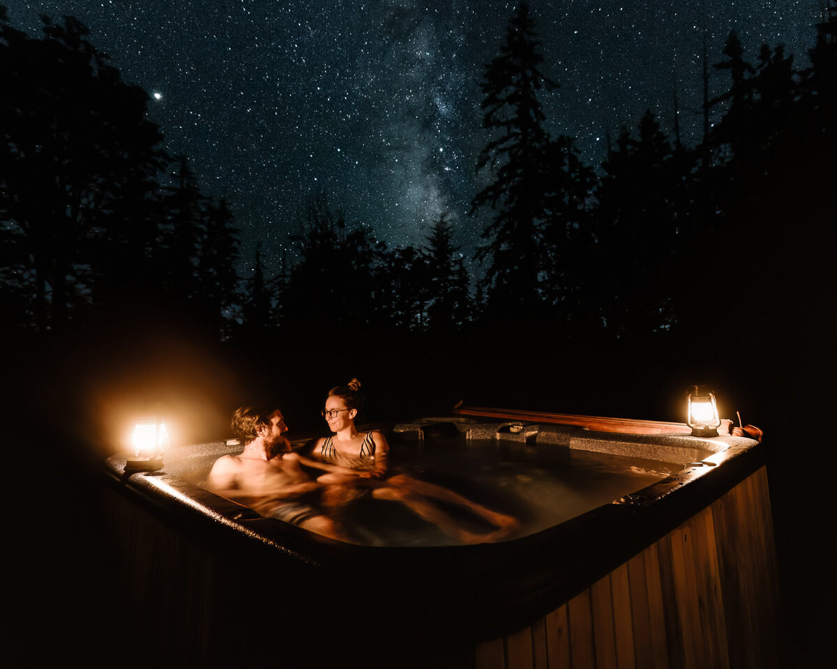 after eloping in washington state, a couple soaks in their hot tub under the starry night sky