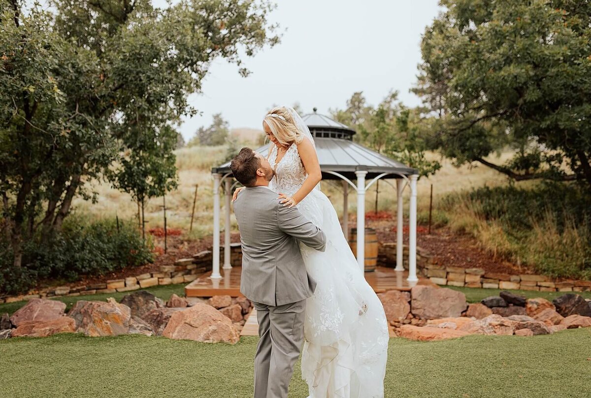 groom lifting bride up for portrait photos on their colorado wedding day