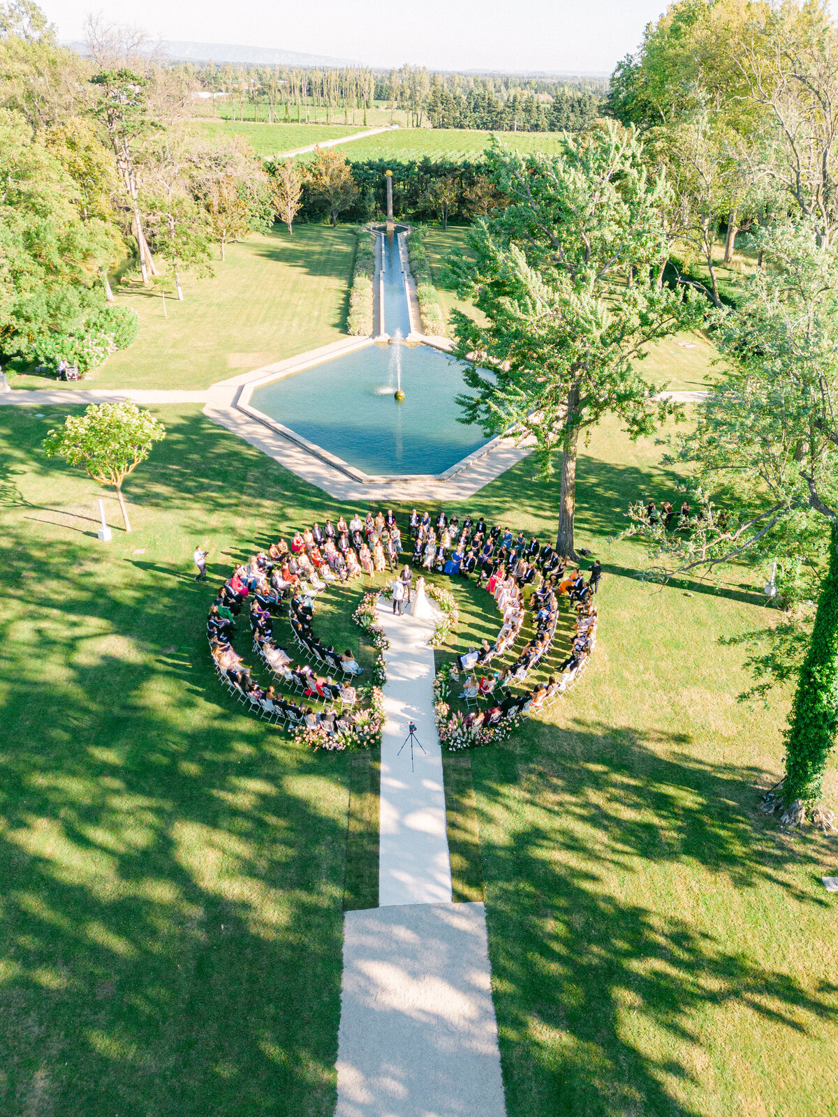 Luxury wedding ceremony in Provence with circular seating around a reflecting pool and fountain.
