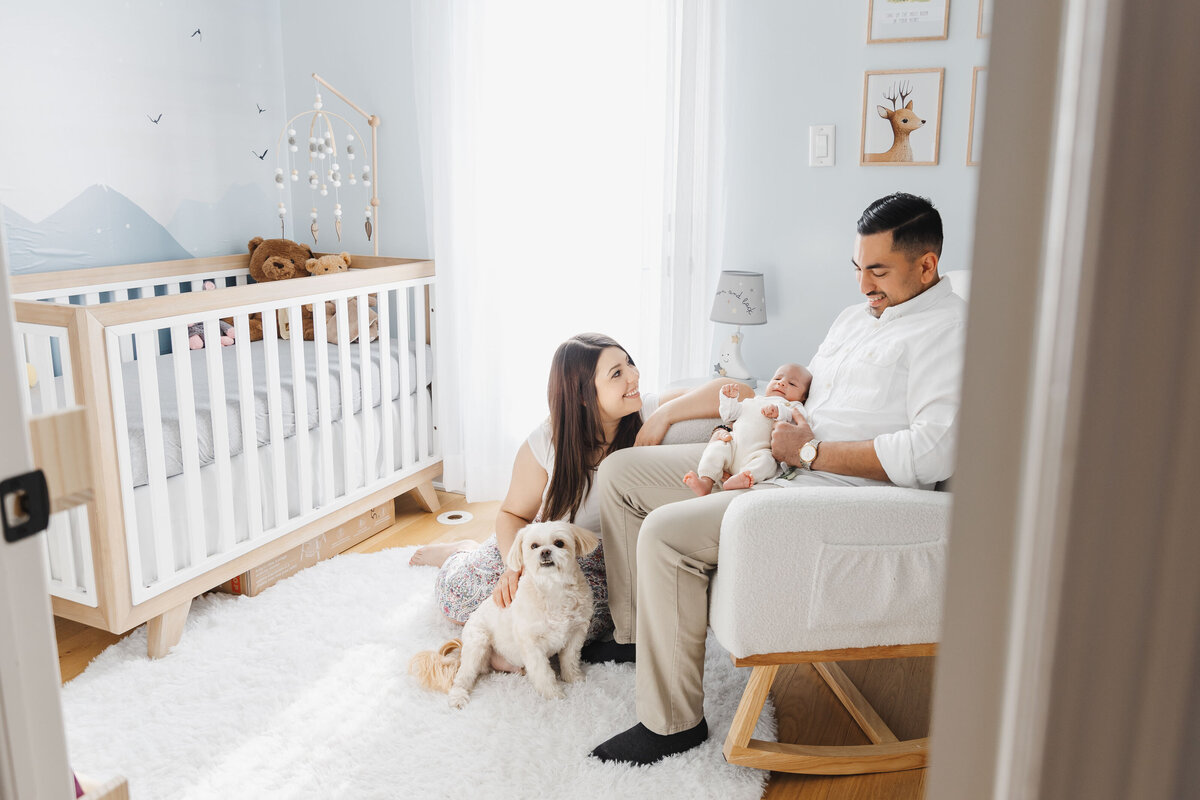 New parents sitting in their baby boys nursery with their pet dog