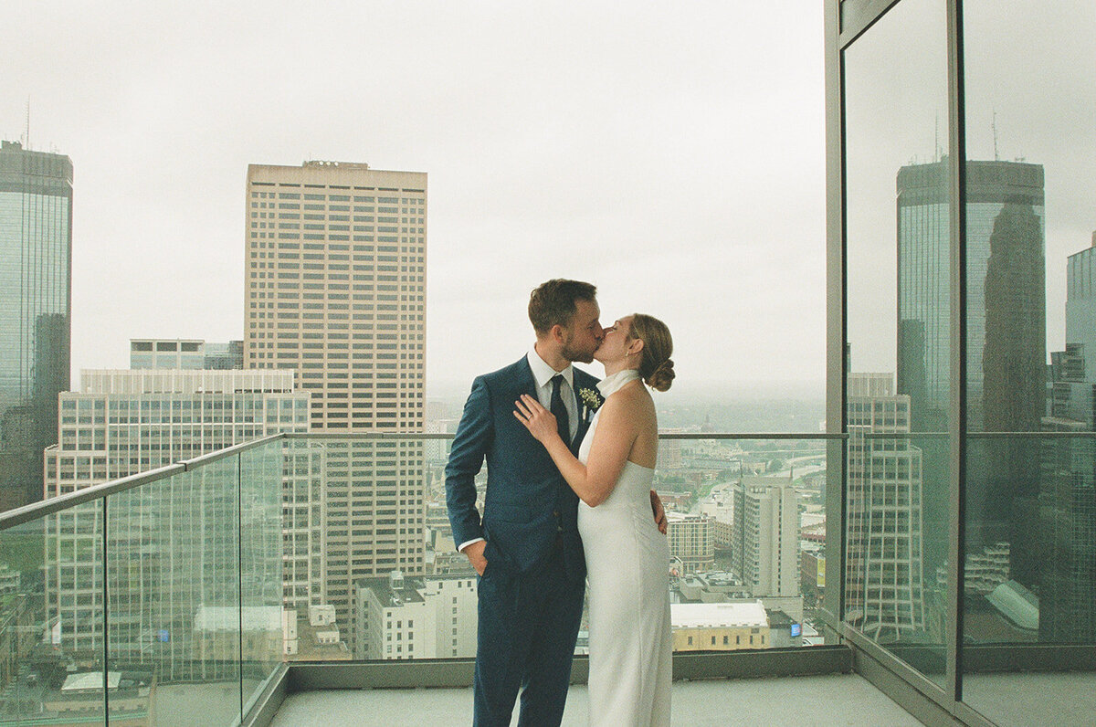couple kissing against Minneapolis skyline on their wedding day