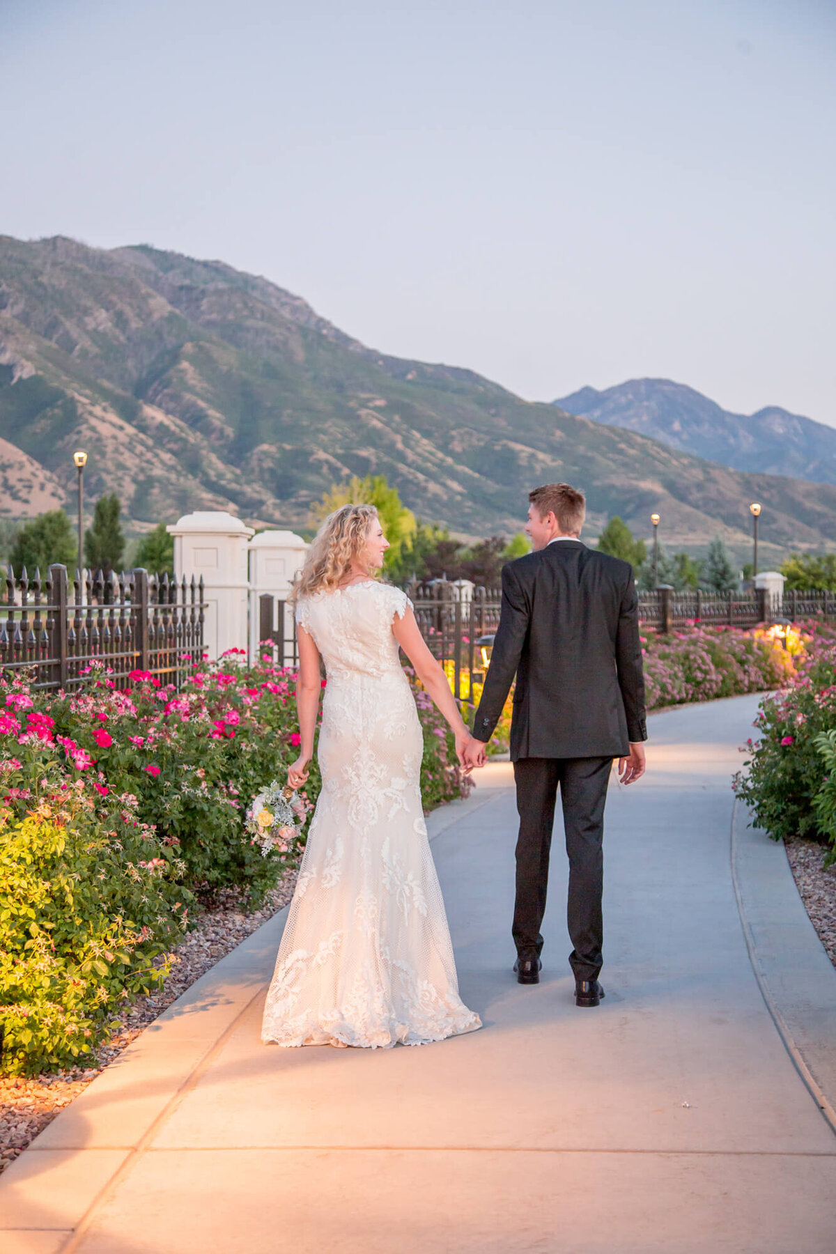 a wedding couple walking at sunset on a flowered path