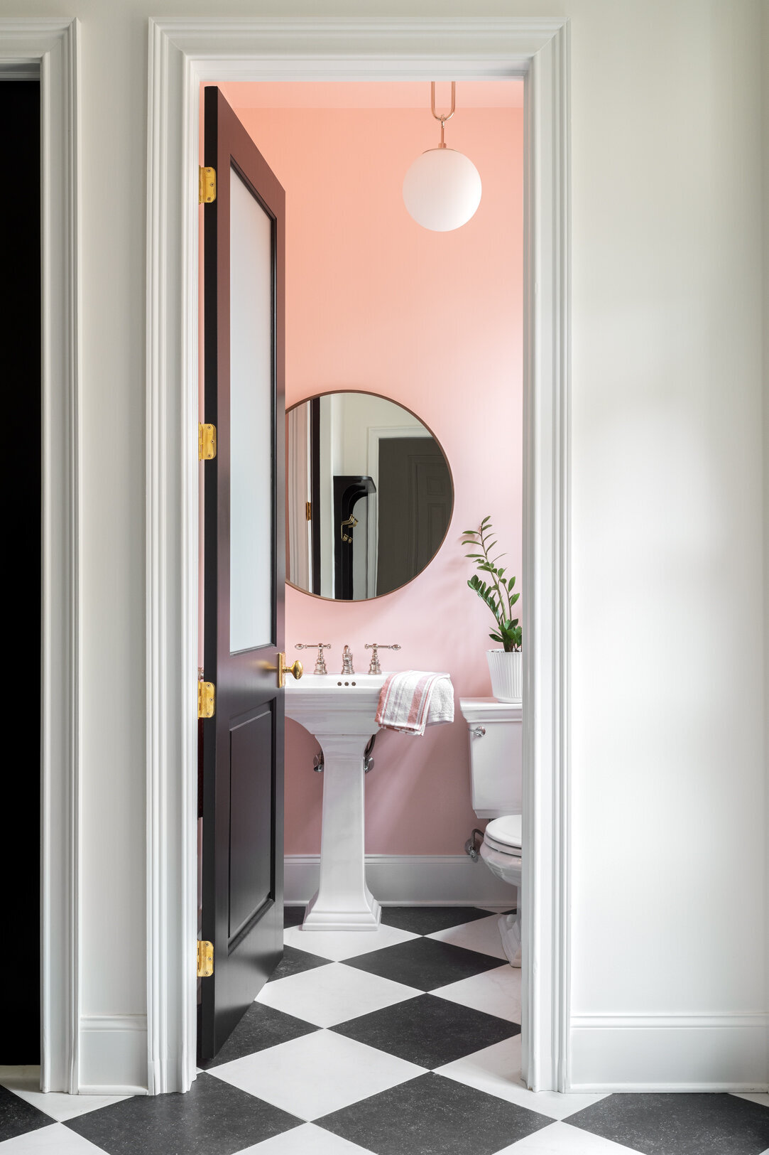 open door to baby pink bathroom with black and white checkered floor