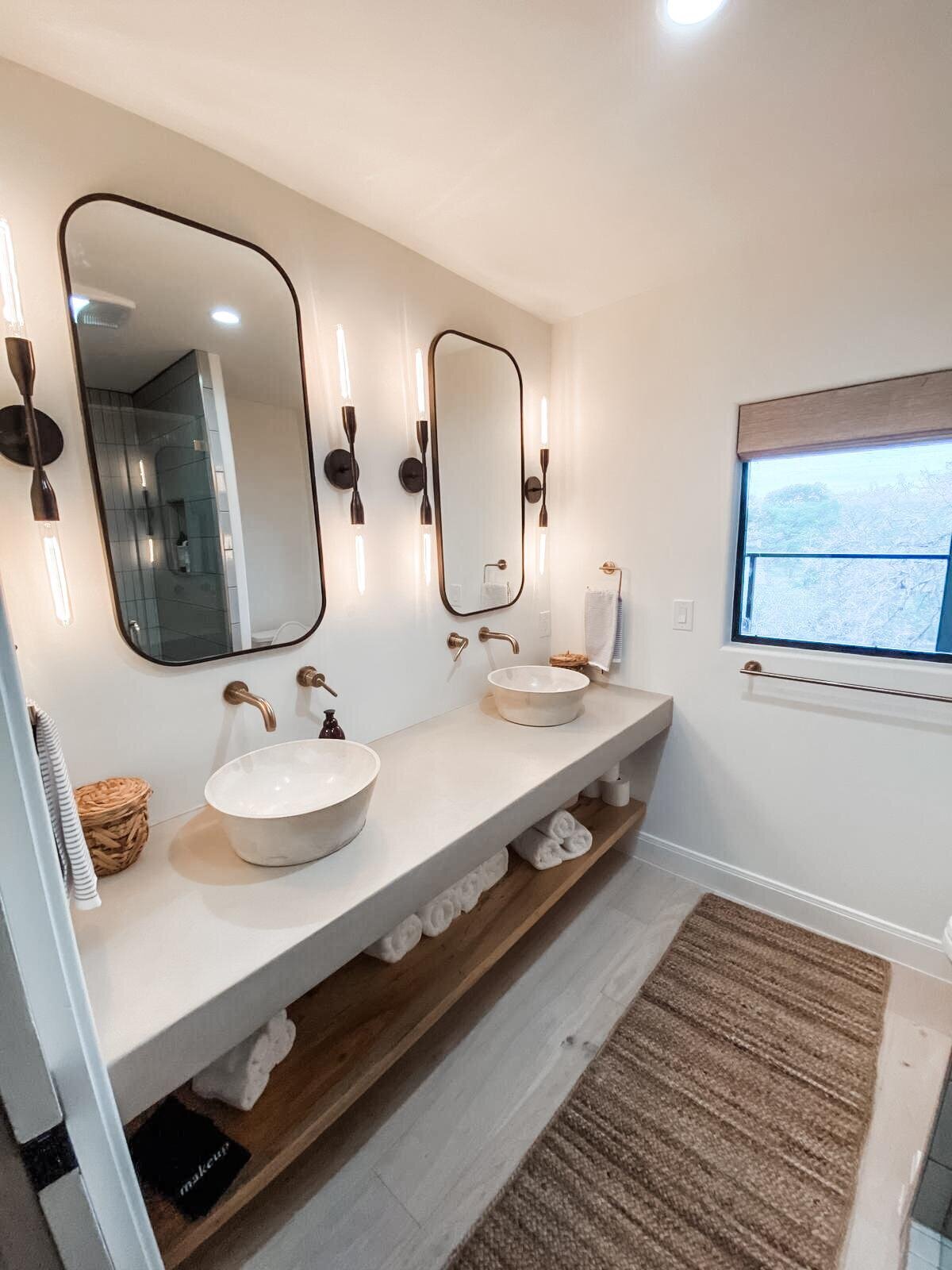 two his and hers sinks side by side with black mirros in a white bathroom