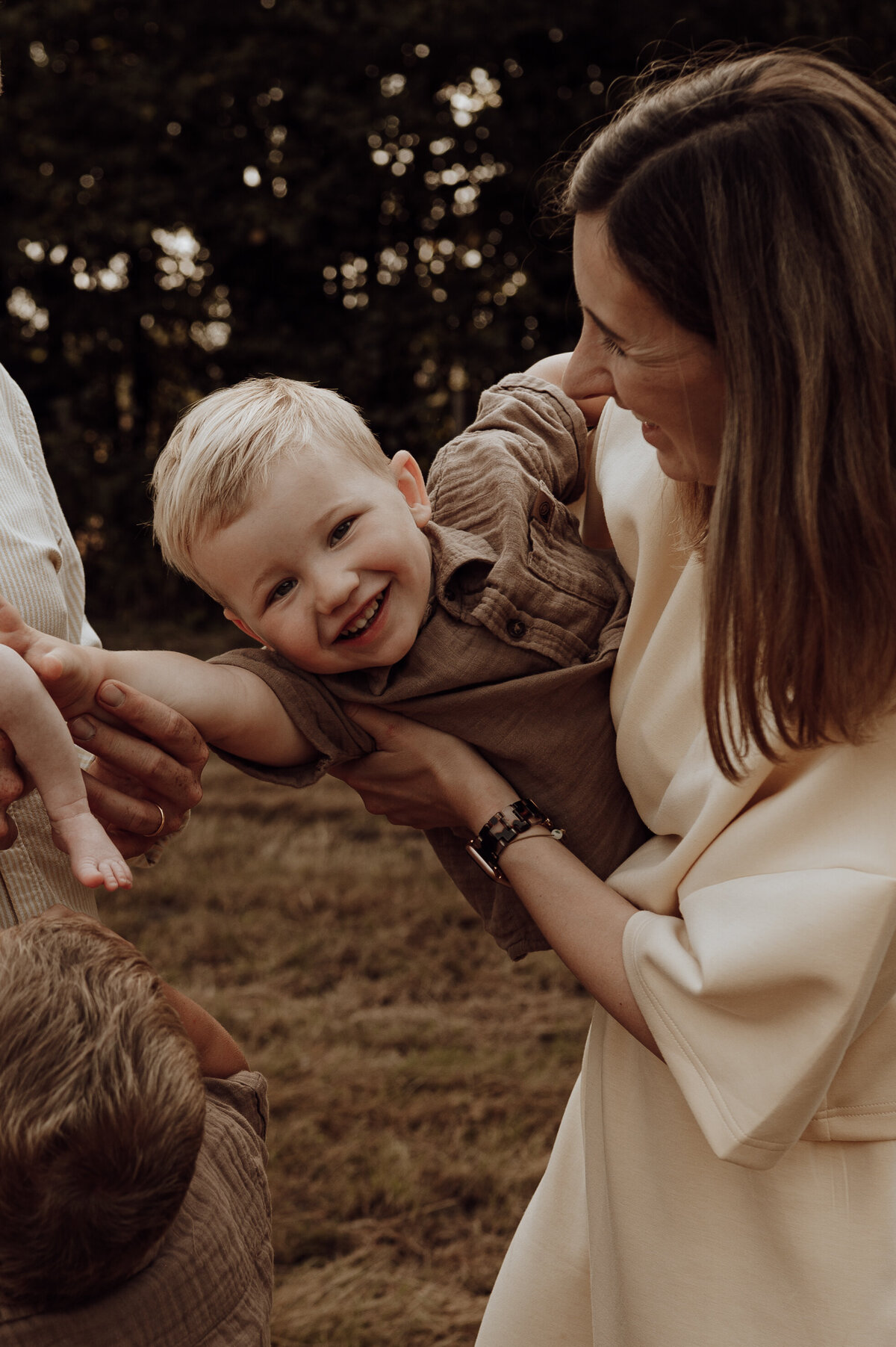 Jongentje lacht in de camera tijdens gezinsshoot in het bos
