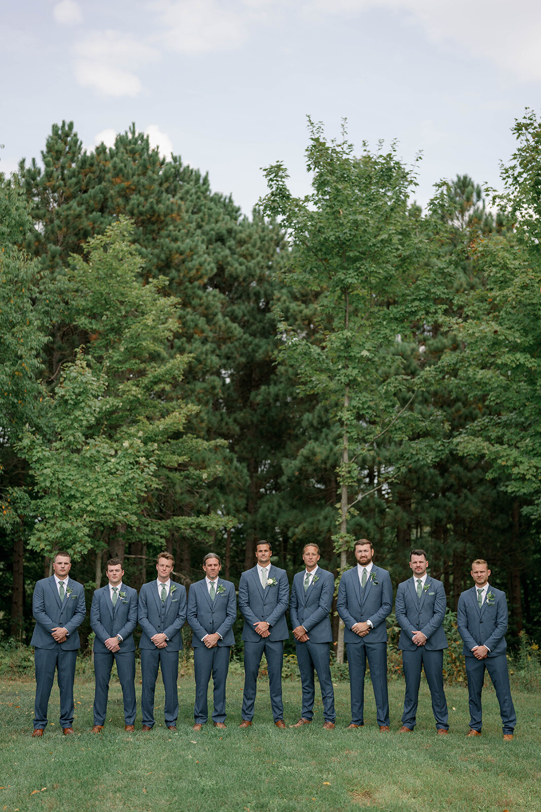 Group portrait of all the groomsmen standing together for formal photos during a Cherry Barn wedding in Frankfort, Michigan.