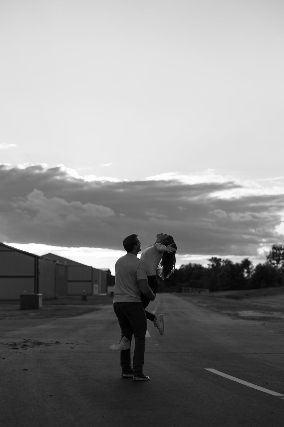 black and white photo of a couple where the guy picks the girls up and spins her around 