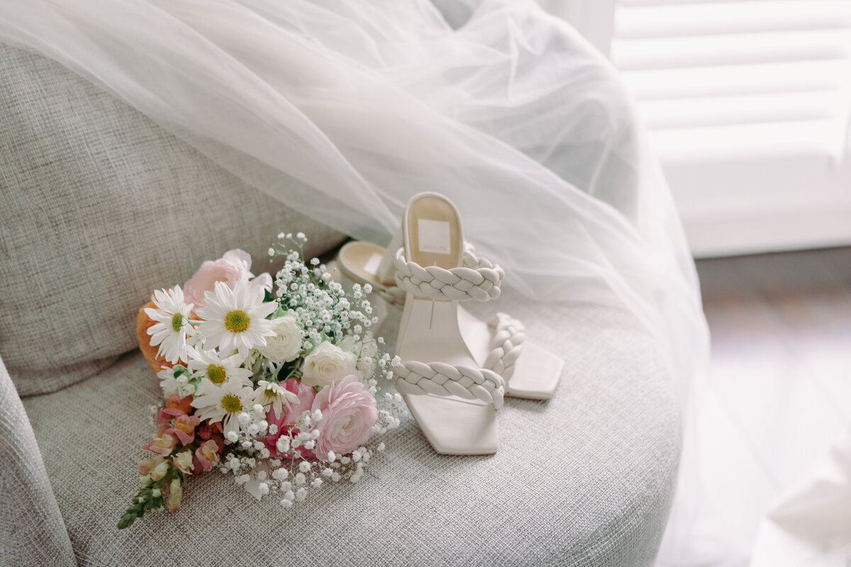 bridal bouquet and shoes laying on a chair with bridal veil