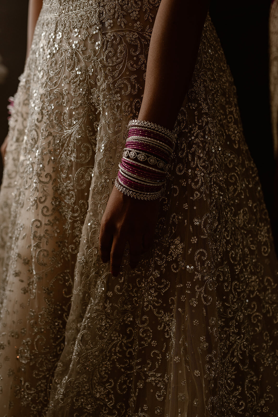 A beautifully detailed South Asian bridal ensemble featuring intricate embroidery, shimmering embellishments, and traditional pink bangles.