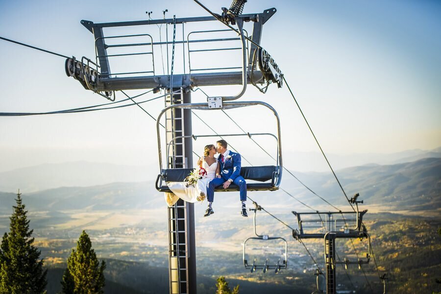 A bride and groom share a kiss on a ski lift, captured by Denver wedding photographer, Casey Van Horn.