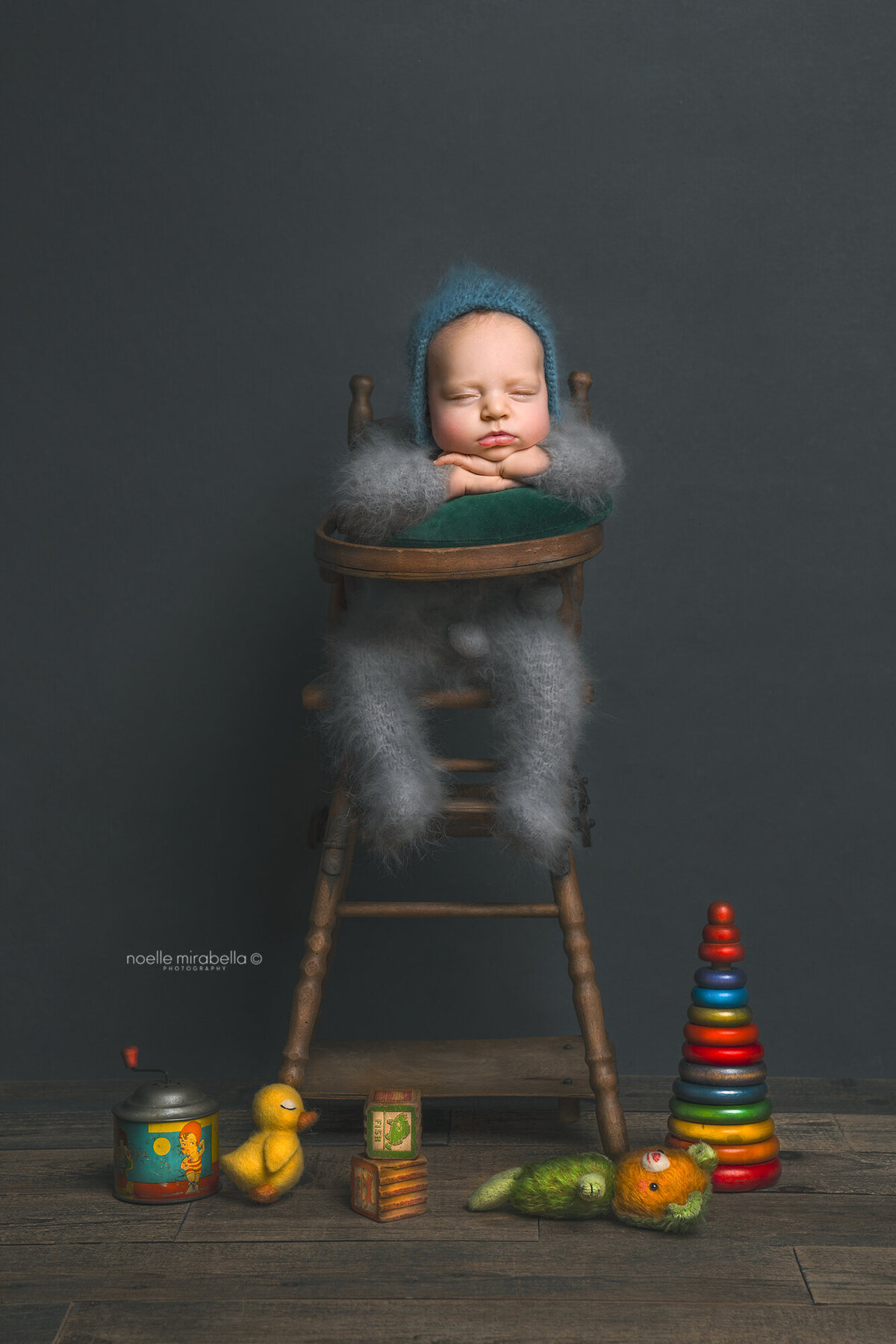 Newborn sleepin in high chair. Vintage toys on the floor.