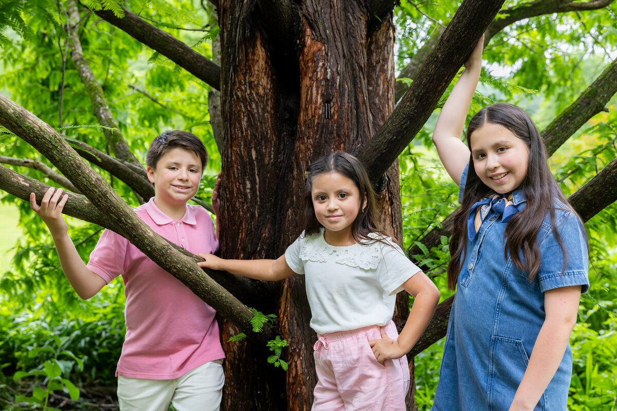 siblings  posing under a large tree during their outdoor session, captured by Capture Joy Photography, Northern Virginia family photographer.