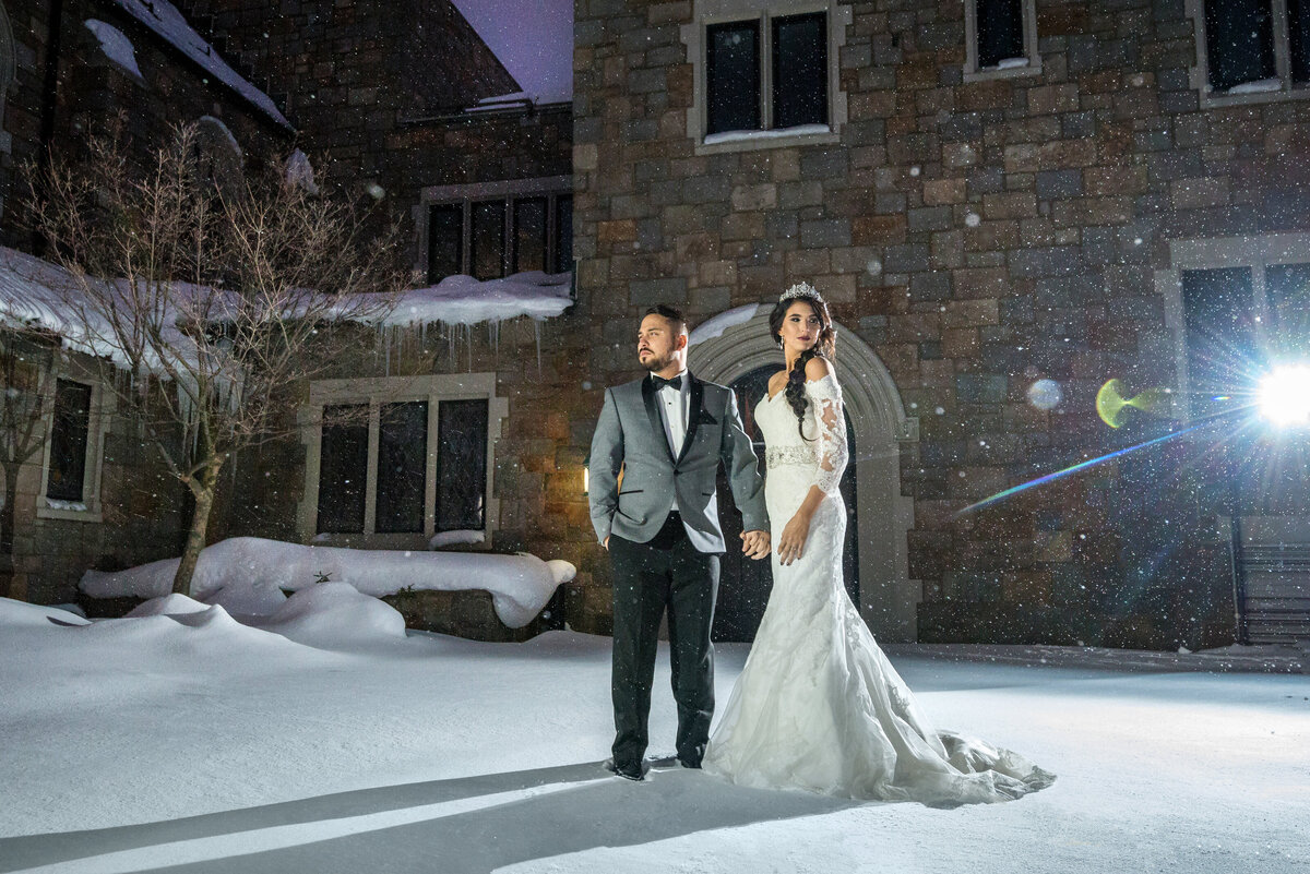 Wedding couple standing in snow for photo session.