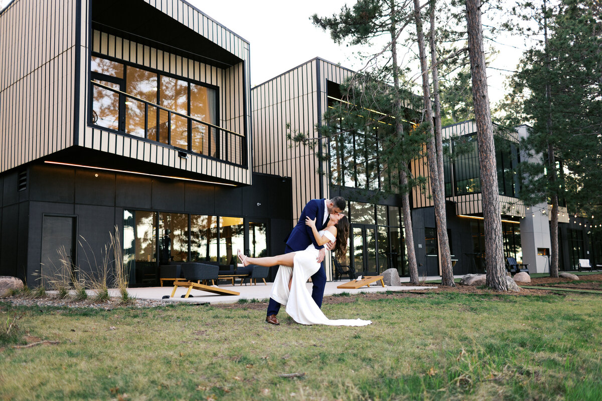 Groom dipping and kissing his bride outside the luxury Catalyst by NatureLink venue at golden hour in Minnesota.