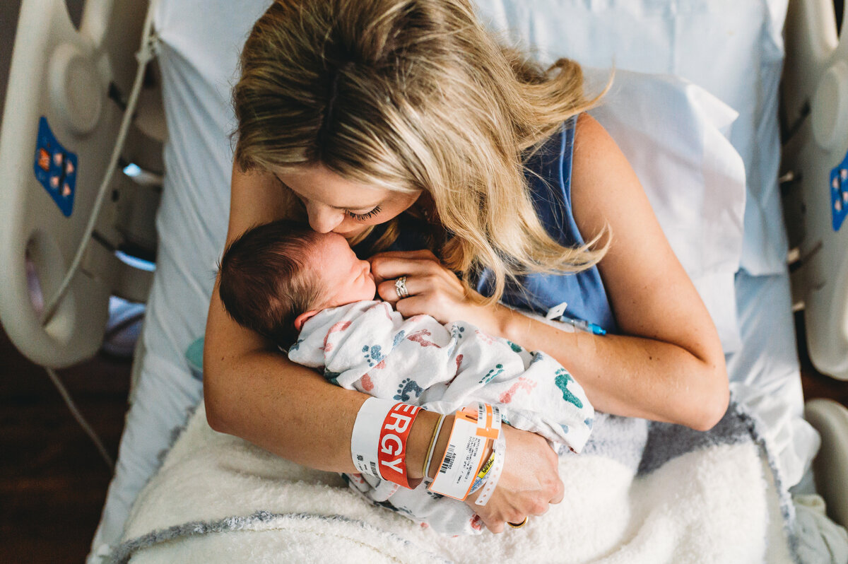 mother holding brand new baby in hospital bed with fall risk bracelet