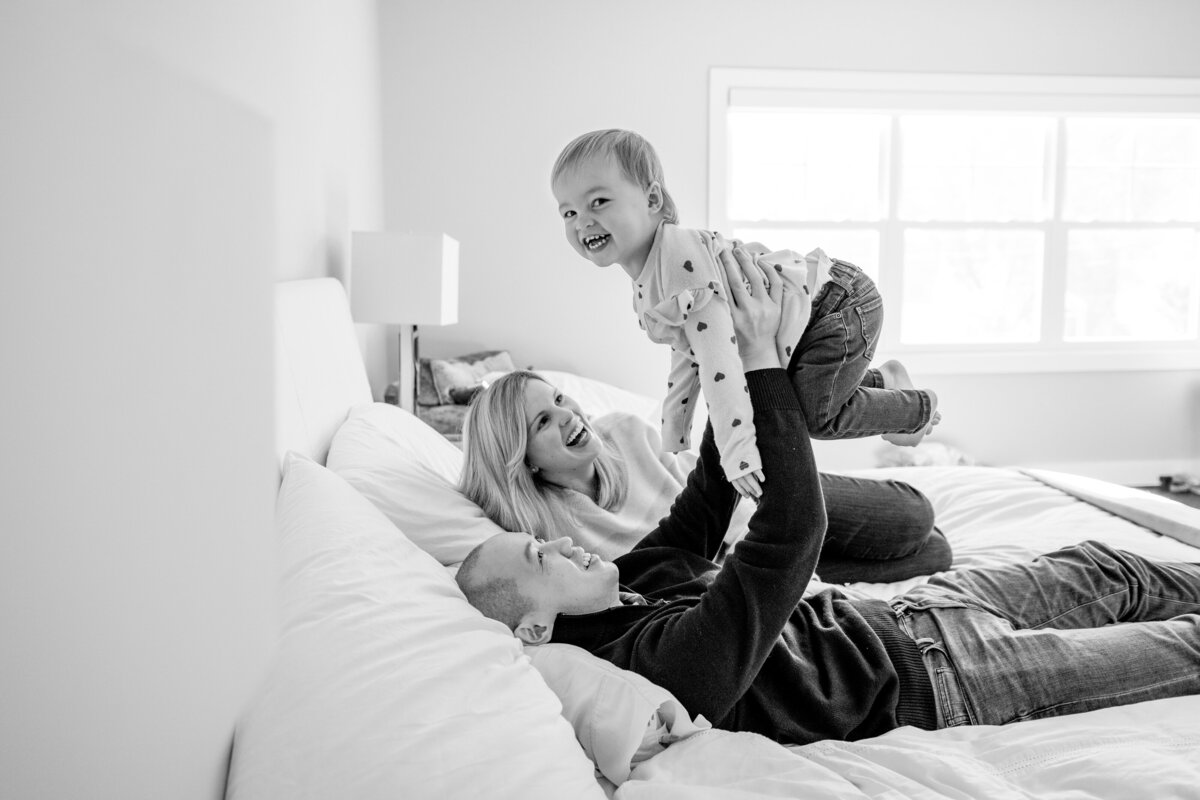 Family of Mom, Dad, and toddler playing on bed