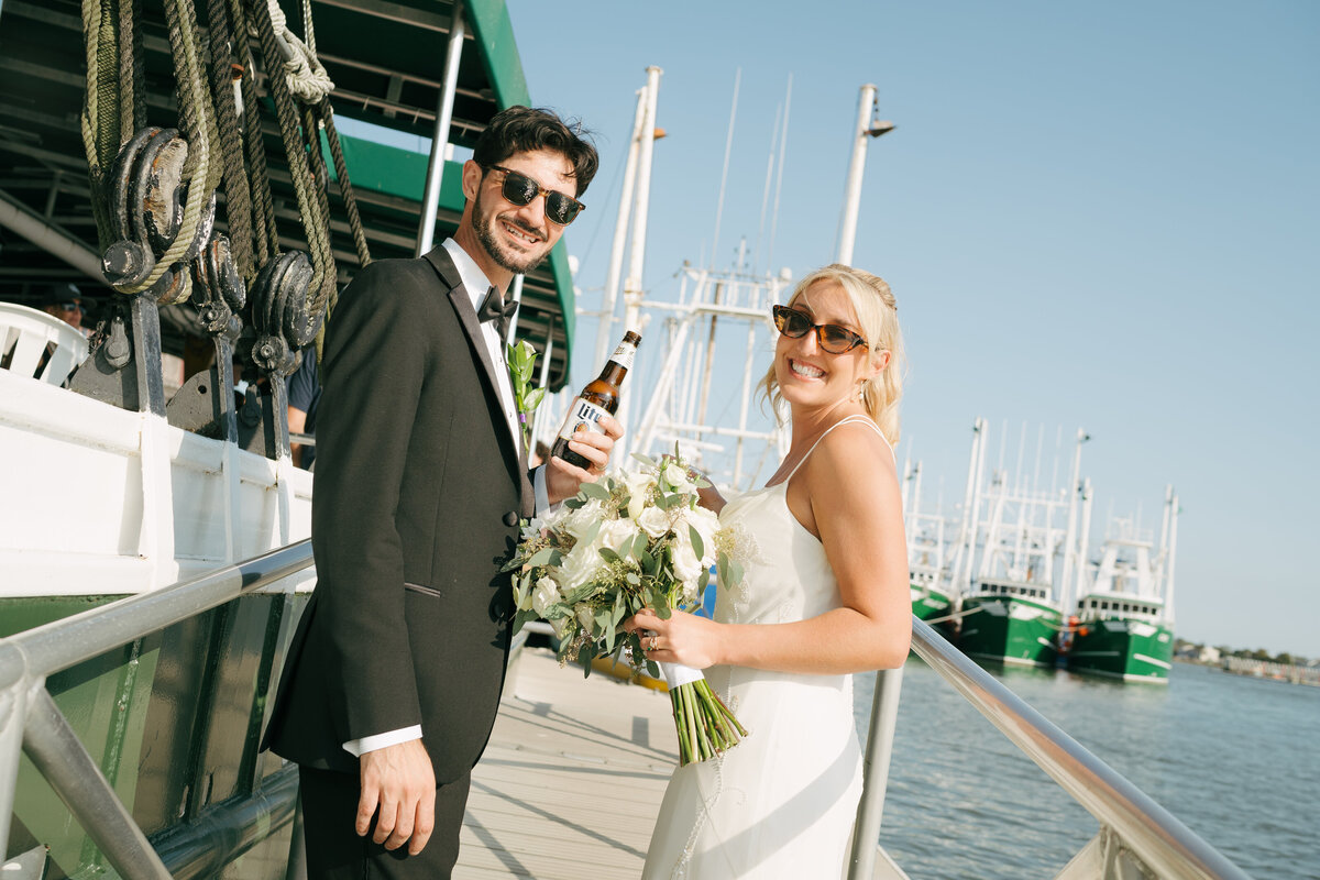 a bride and groom are looking back at the camera as they walk around the marina at the Lobster House in New Jersey.