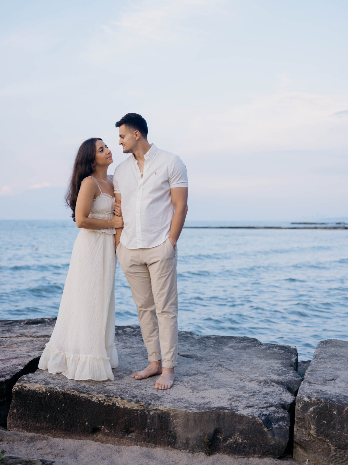 Soft sunset tones surrounding a couple looking into each others eyes during their beach engagement.