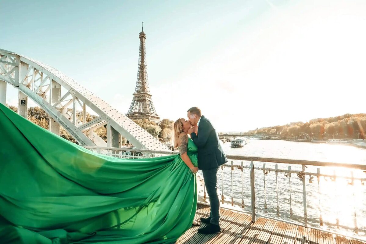 a couple having a photoshoot in front of the eiffel tower with a green flying dress