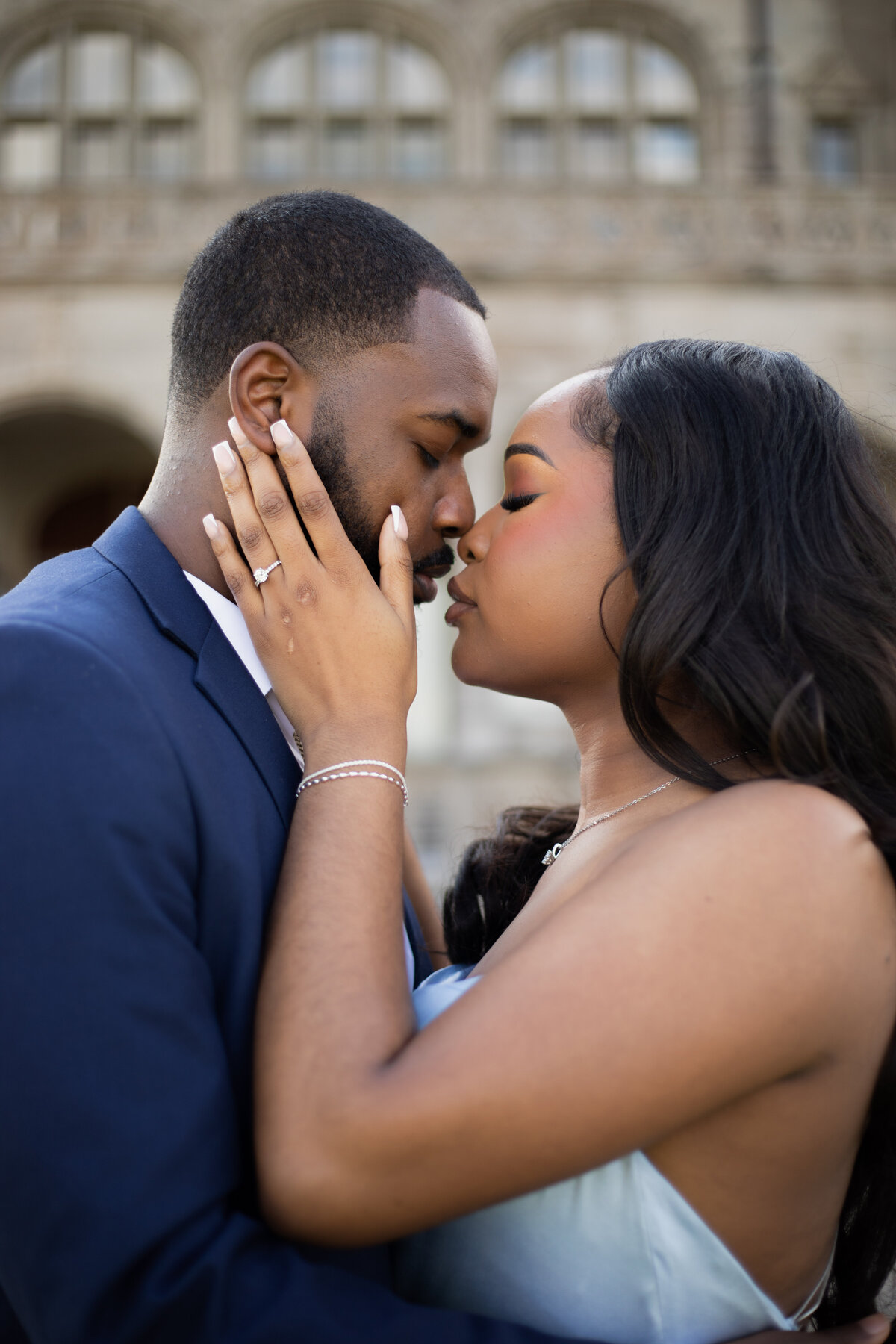 Wedding Photographers in RI | Kelsey Sheehan Photography Timeless Rhode Island Weddings | A couple stands close, eyes closed, about to kiss. The woman gently touches the man's face, showcasing an engagement ring. The mood is romantic and intimate.