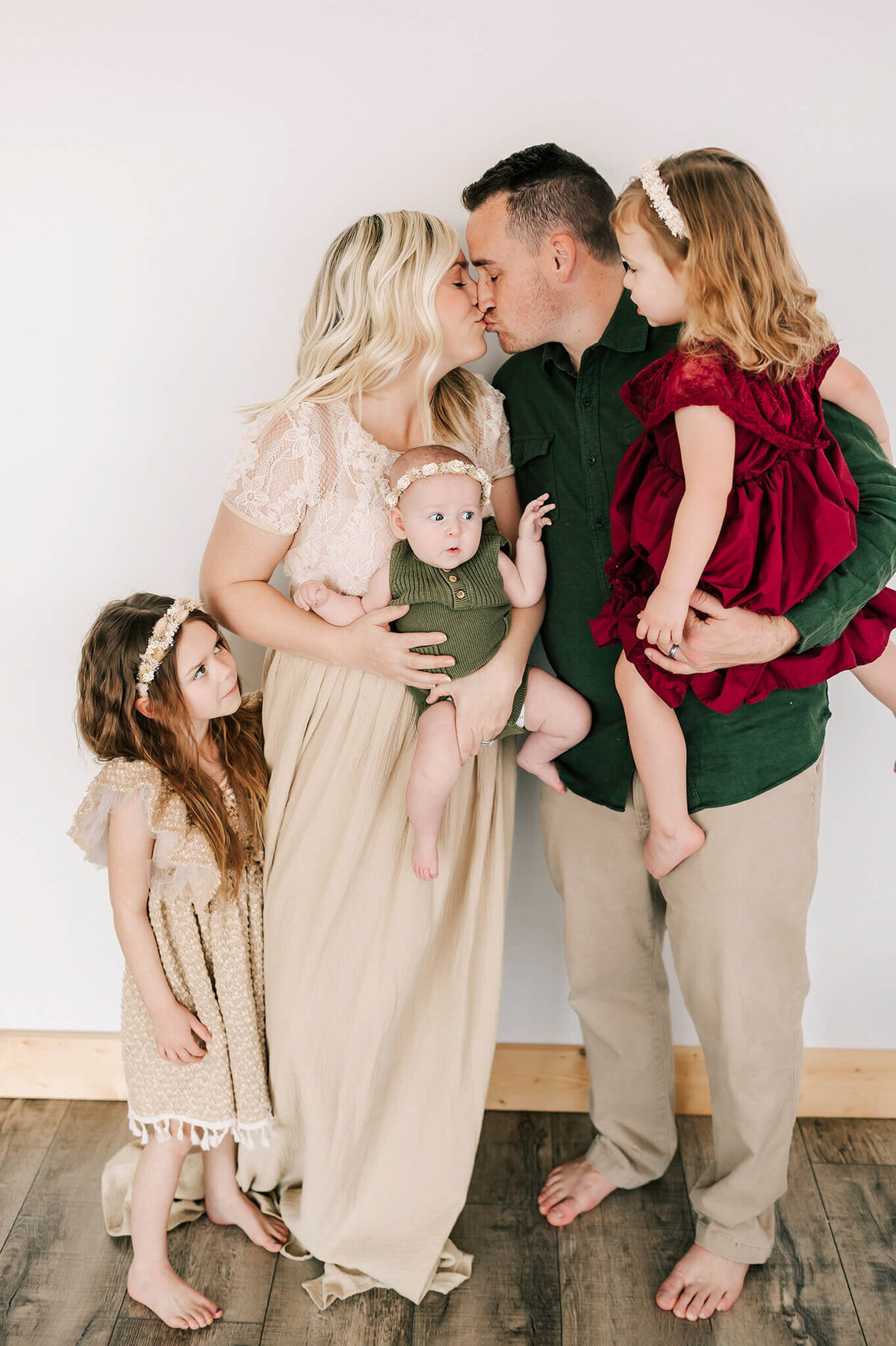 parents kissing holding kids during Branson Mo family photography session