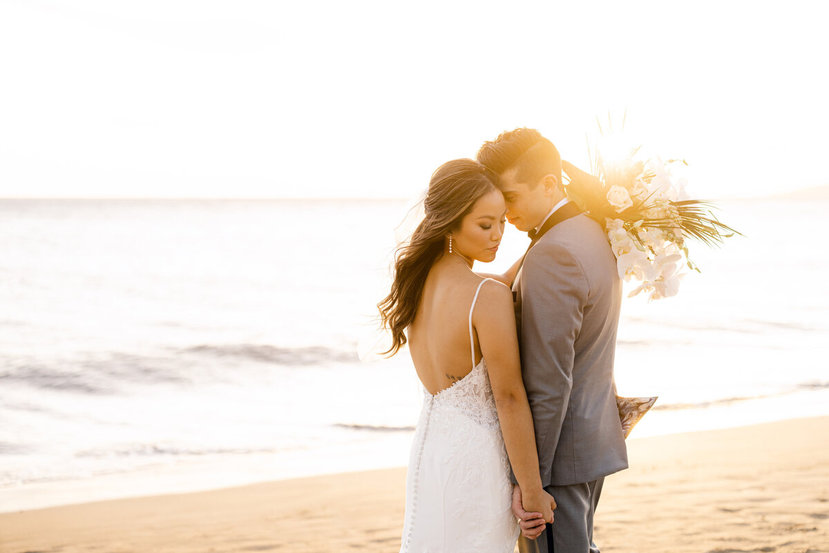Maui wedding couple posed on beach with sunset flare