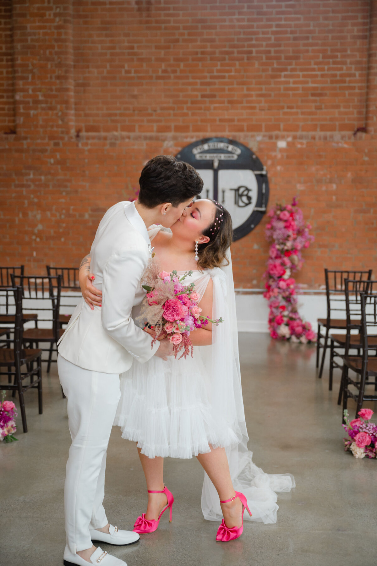 Two brides kissing on the wedding aisle