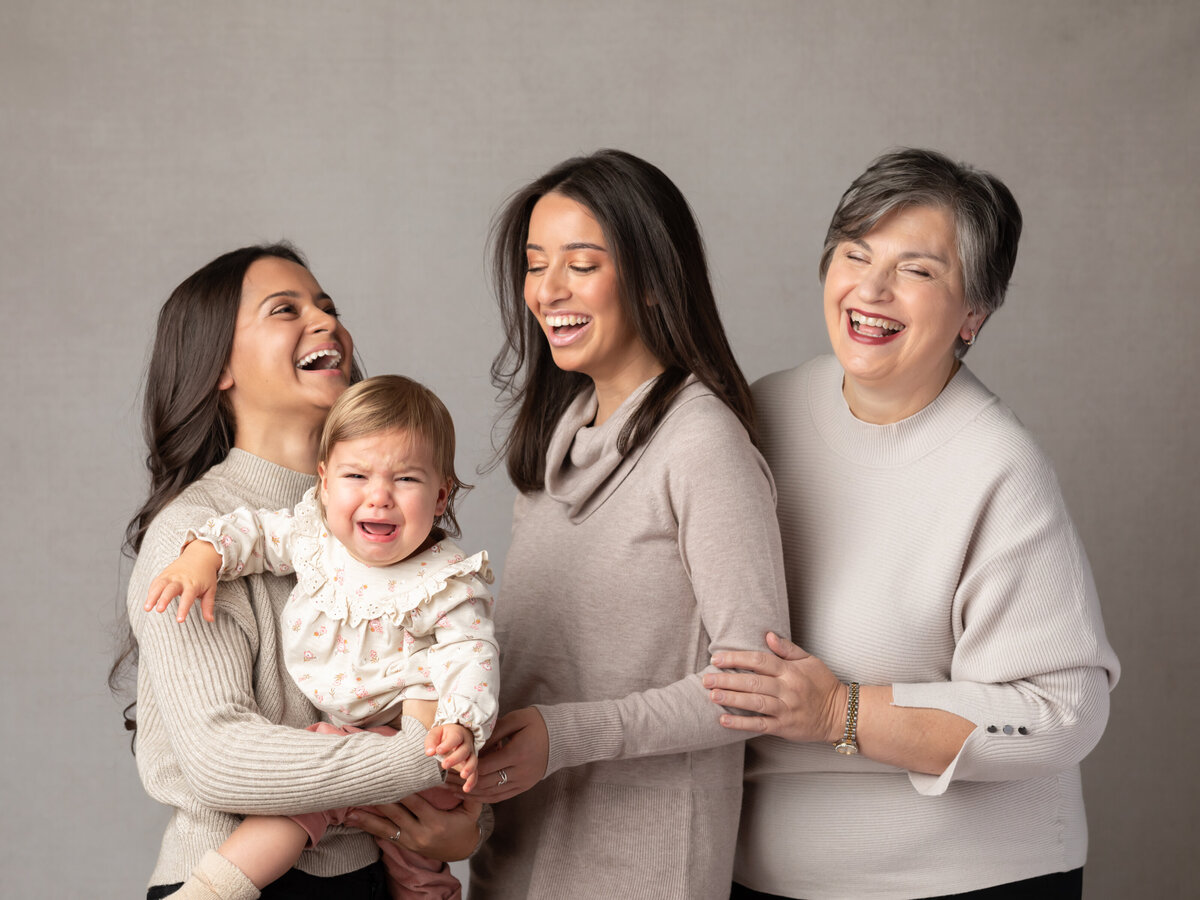 grandma and three granddaughters posing for studio portraits