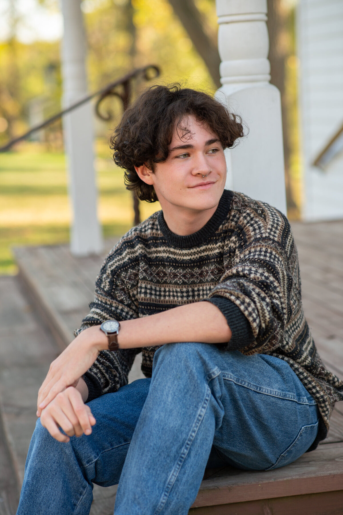 High-school senior portrait of a young man sitting on the wooden porch steps at Beckman Mills in Beloit.   