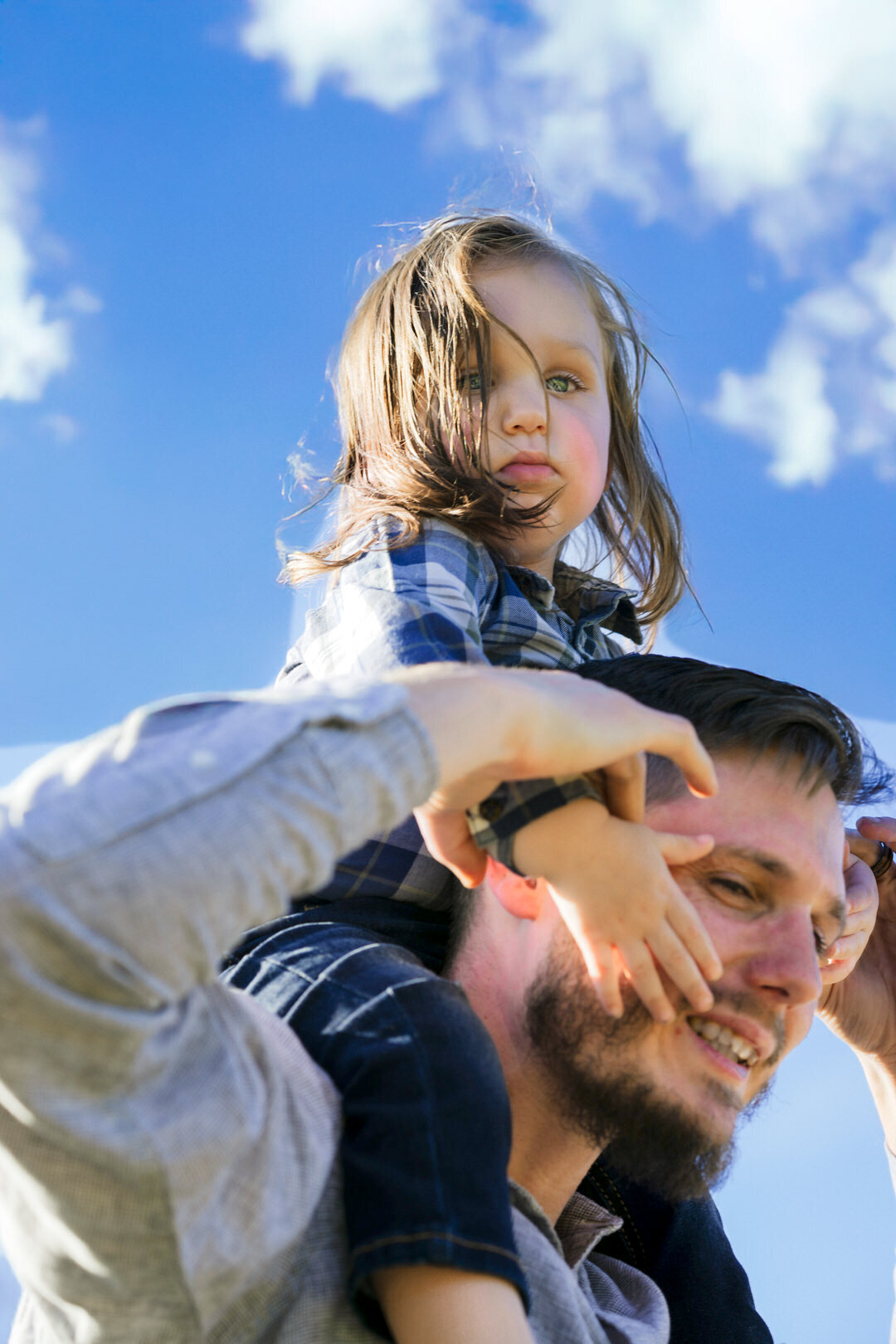 Outdoor family portrait of toddler on dads shoulders