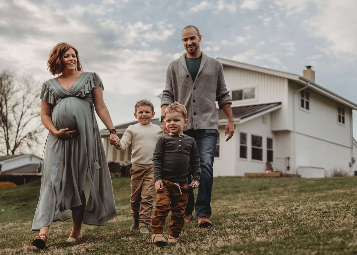 A family walking in front of a house captured by a Pittsburgh maternity photographer.