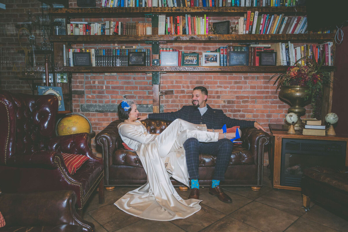 Bride puts feet on top of groom surrounded by books in Jersey City.