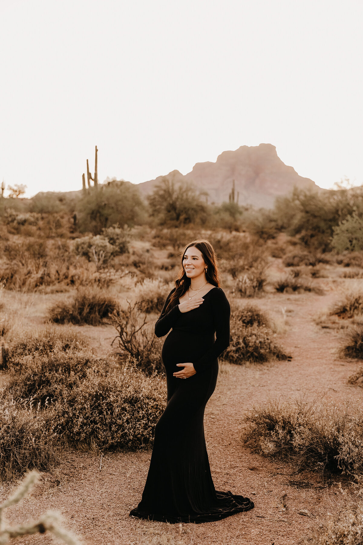 mom posing at sunset in black dress for phoenix maternity session