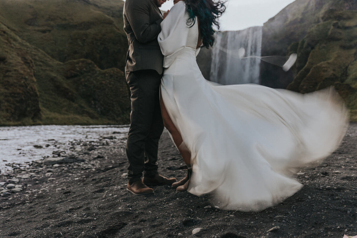 In a quiet, intimate moment, a husband and wife kiss near a secluded waterfall