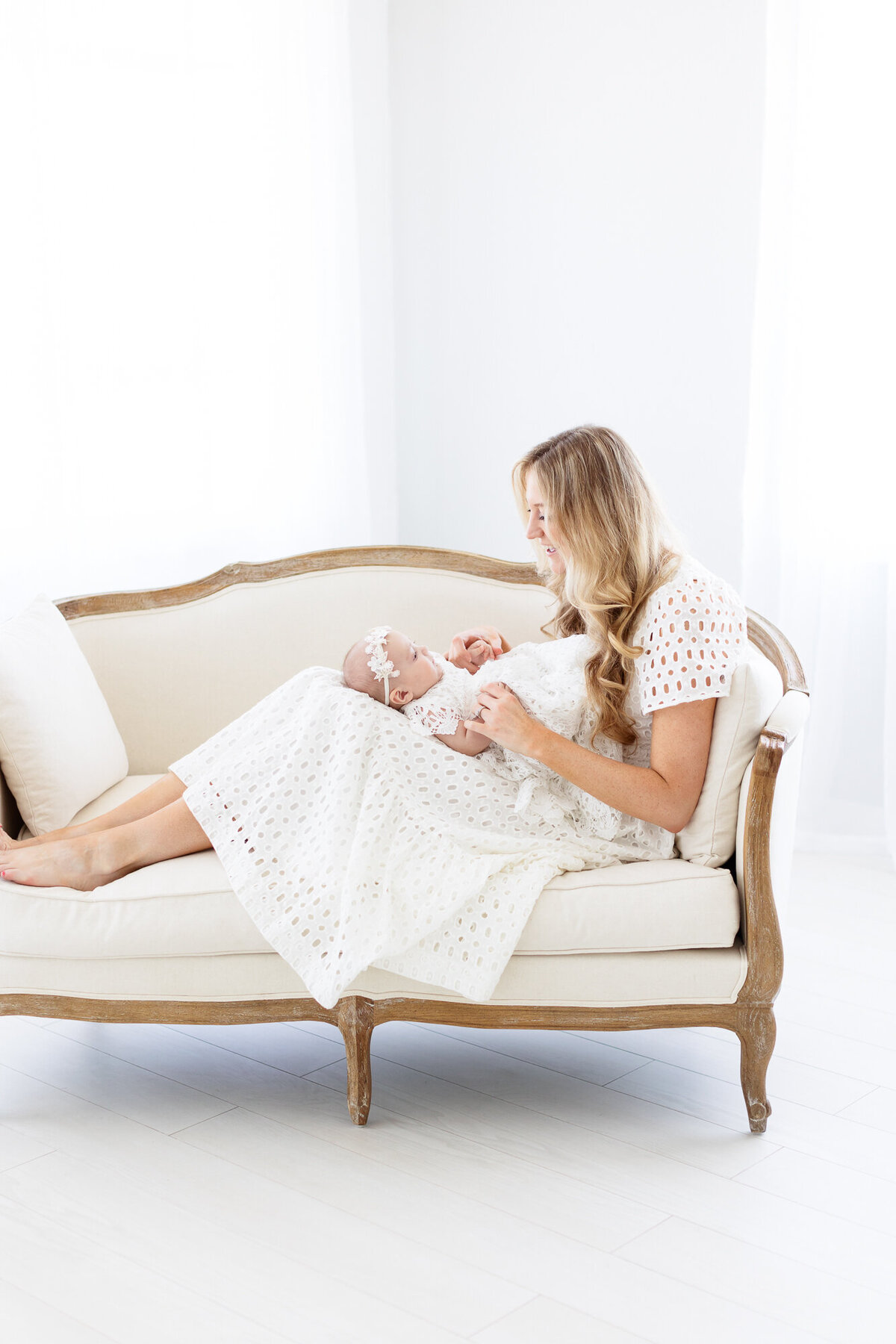 Mom sitting in a settee with baby on her lap in while Boise photography studio.