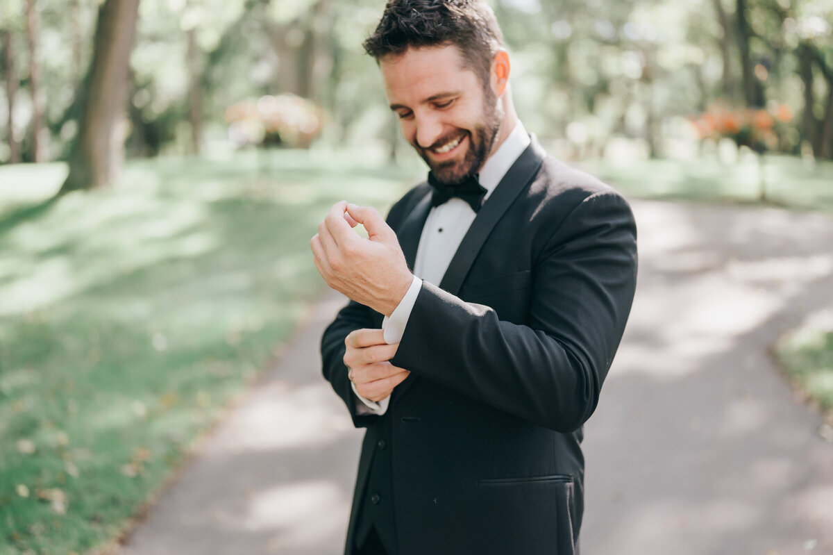 Candid of groom adjusting suit during outdoor portraits photographed by Nova Markina