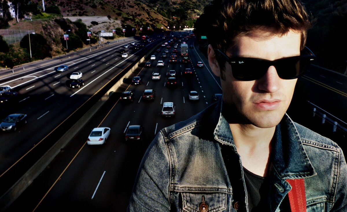 Male musician portrait Dave Green wearing sunglasses blue jean jacket freeway traffic behind