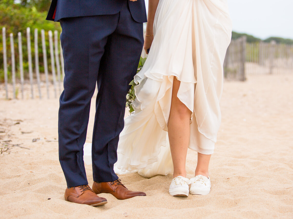Bride and groom stand on a beach on their wedding day.