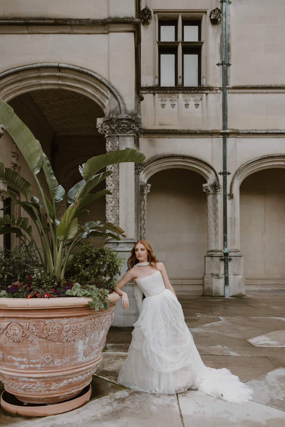 Bride in a Watters gown from Anthropologie posing gracefully in front of the Biltmore House.