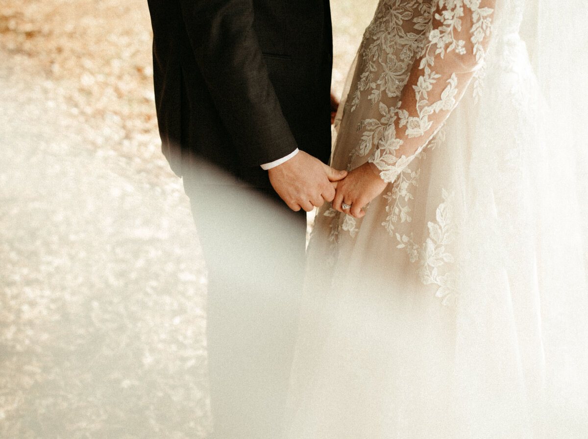 Bride with long lace sleeves holding hands with her groom
