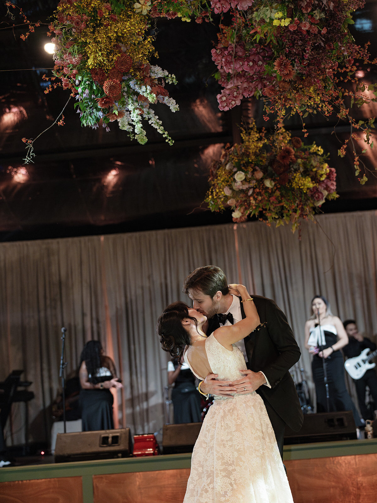Interacting and sculptural floral clouds hang over the dance floor and bars of this fall wedding reception in Tennessee. Clear top tent build out for fall wedding reception in Tennessee hills.  Product clustered floral clouds in a tasteful fall color palette of copper, ruby, gold, burgundy, rust, and lavender. Orchids, bittersweet berries, butterfly ranunculus, and tulips are highlighted. Unique floral design with flower forward large scale installations. Design by Rosemary & Finch Floral Design in Nashville, TN.