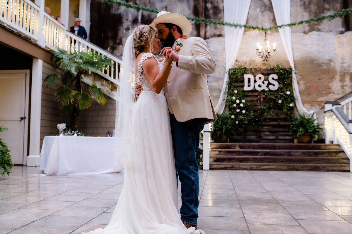 bride and grooms first dance on their wedding day for their indoor wedding reception with their rustic wedding decor in the background